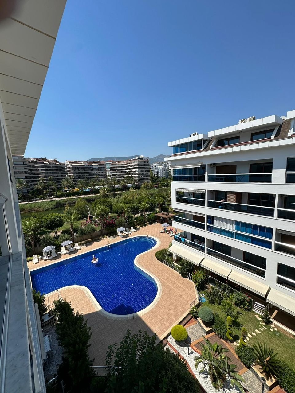 Blick vom Balkon der Maisonette auf die Schwimmbadanlage und den Gebirgsfluss